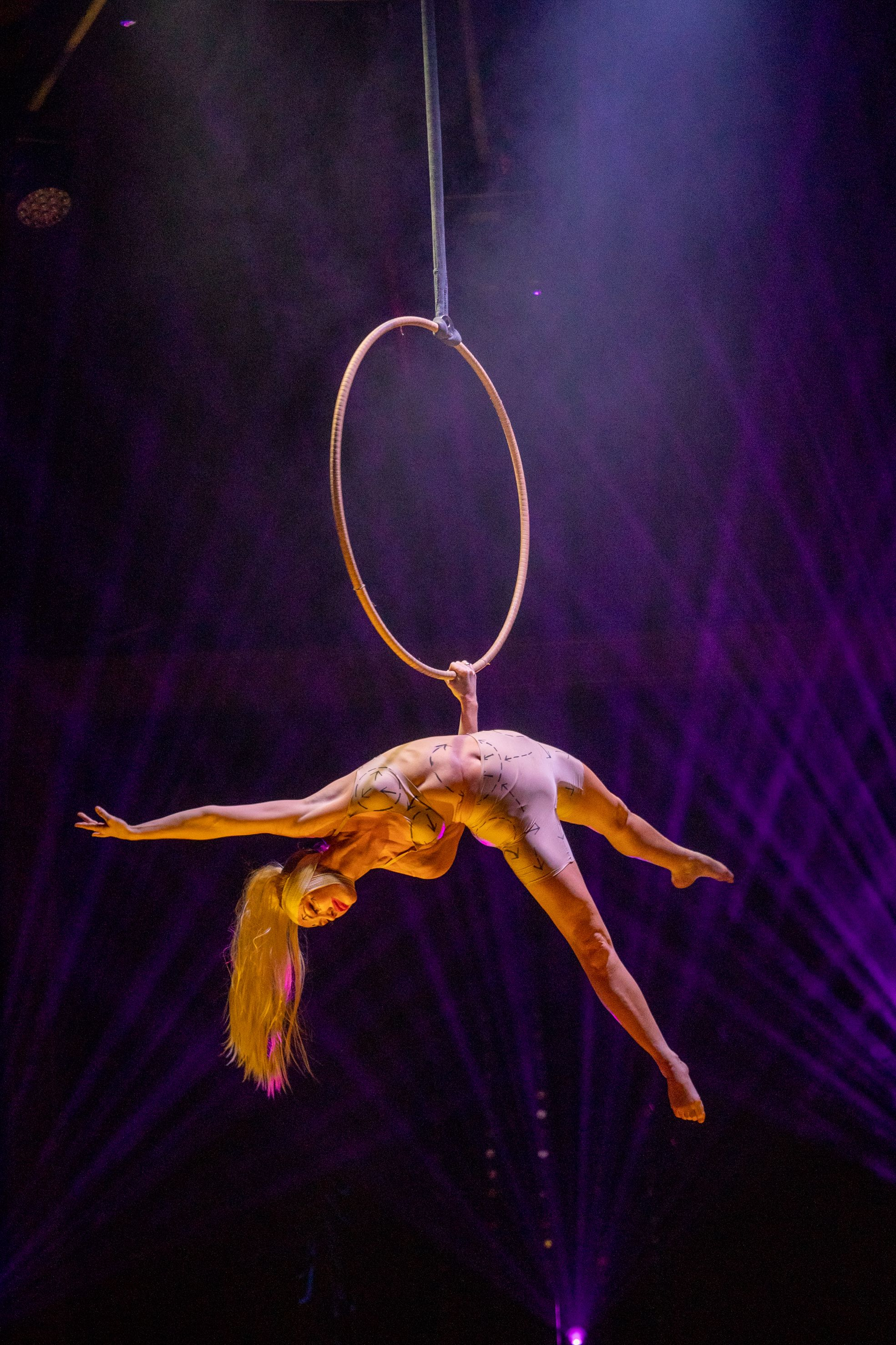 A woman hangs from a hoop by one hand.