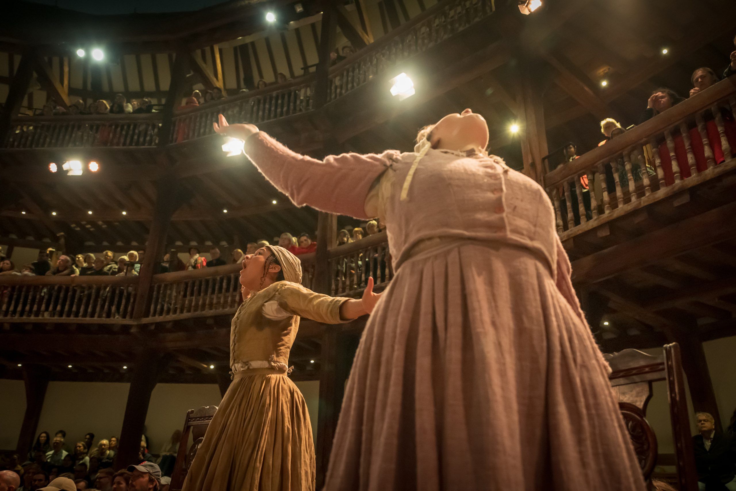 Aisha-Mae McCormick as Susanna Walcott and Molly Madigan as Mercy Lewis cry out and gesticulate in the Globe’s courtyard, their faces lifted to the heavens as the audience looms above.