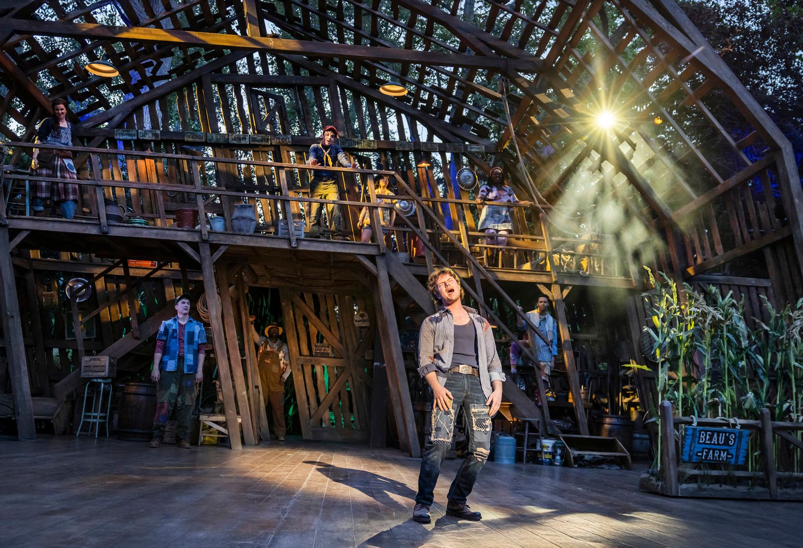 Ben Joyce stands alone front and centre, belting out a number with raw emotion, as cast members look on from a two-level wooden barn set behind him.