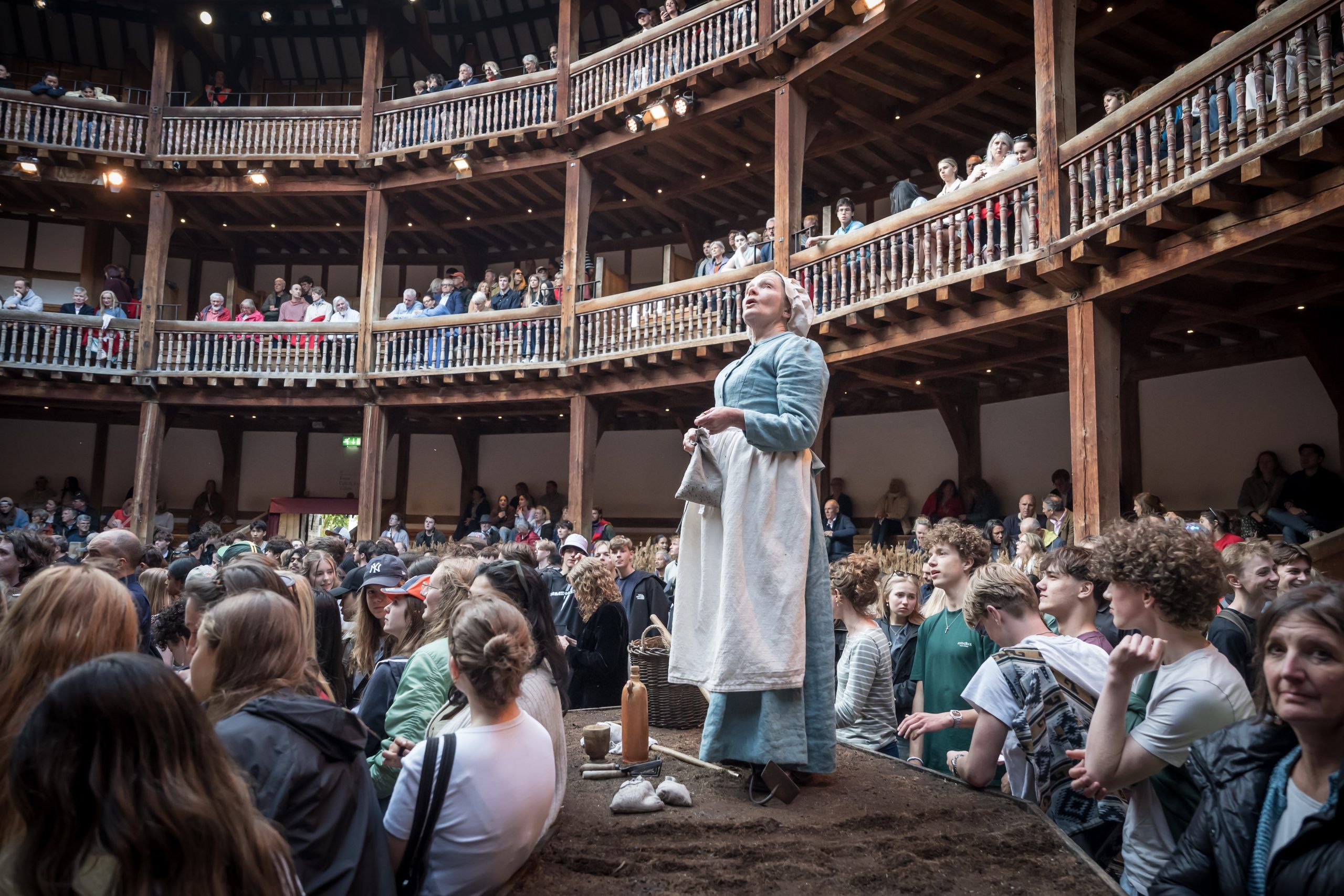 Joanne Howarth as Rebecca Nurse stands barefoot on the dirt mound in the centre of the Globe’s yard, calm and composed amid a crowd of modern-day groundlings.