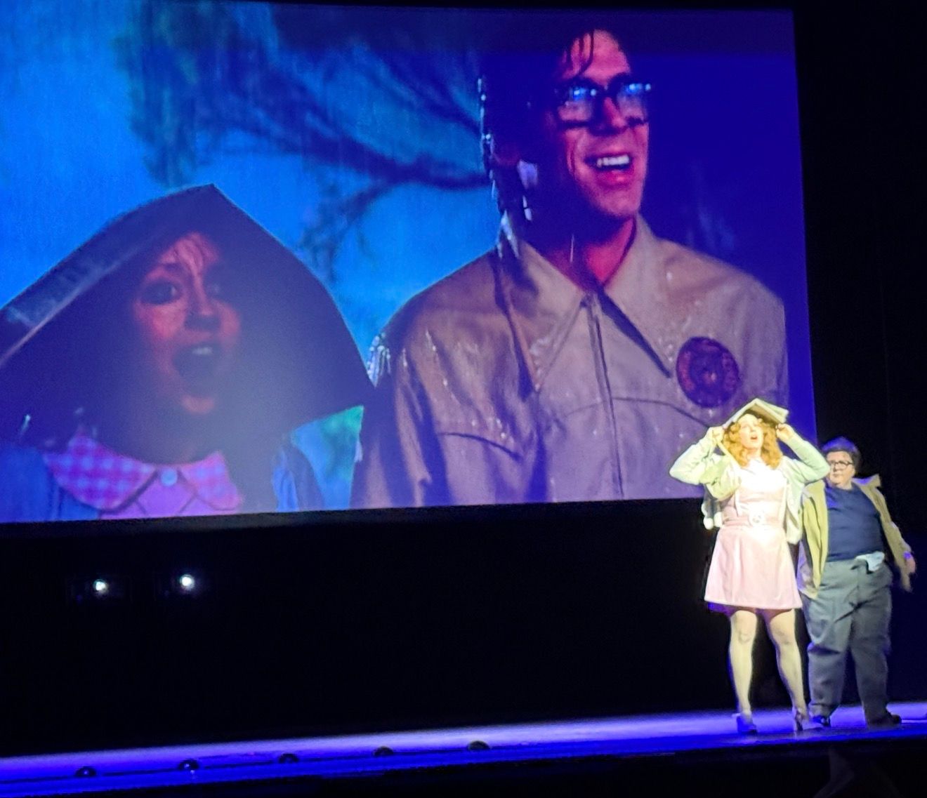 Shadow cast performers recreating Brad and Janet beneath the film screen