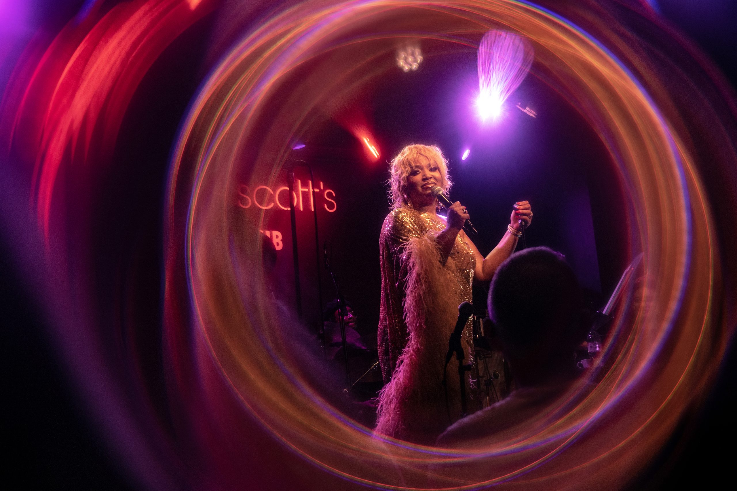 Marisha Wallace performing at Ronnie Scott’s, framed by a circle of coloured light
