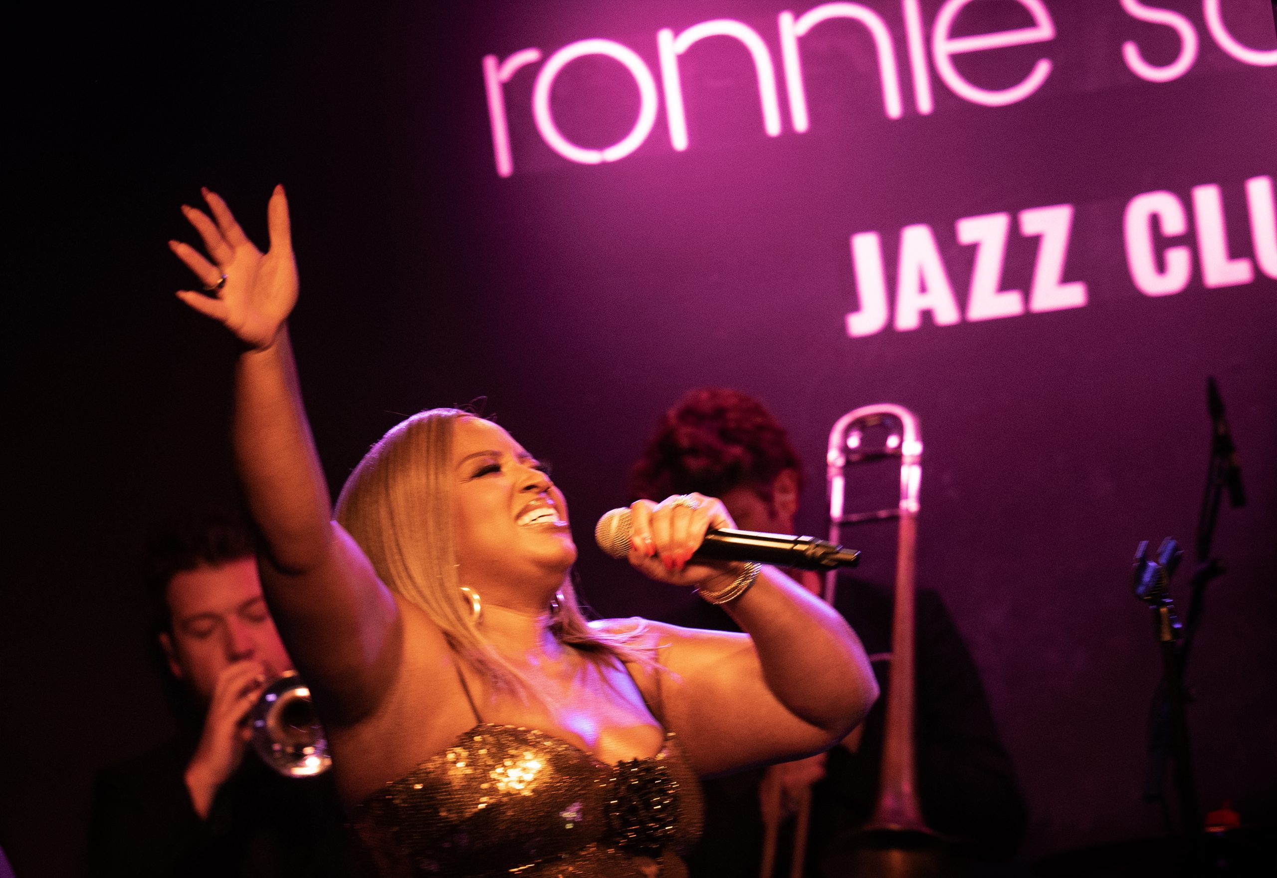 Marisha Wallace singing with one hand held high at Ronnie Scott’s